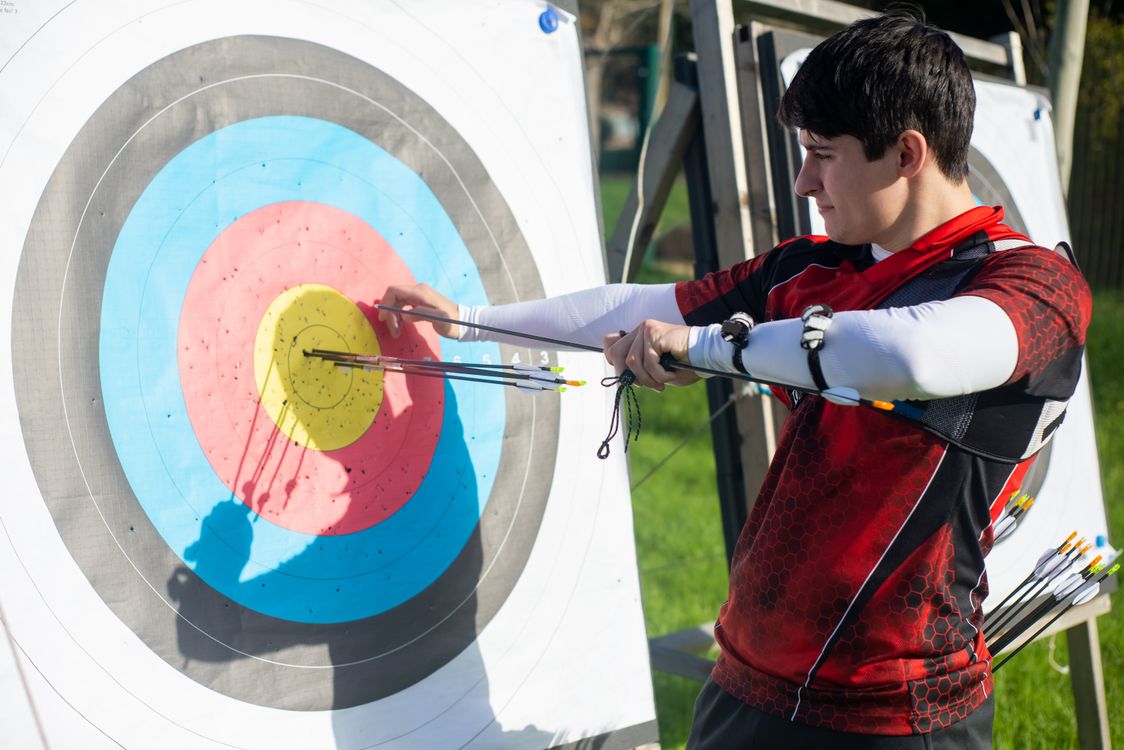 Archer vérifiant ses flèches sur une cible en extérieur