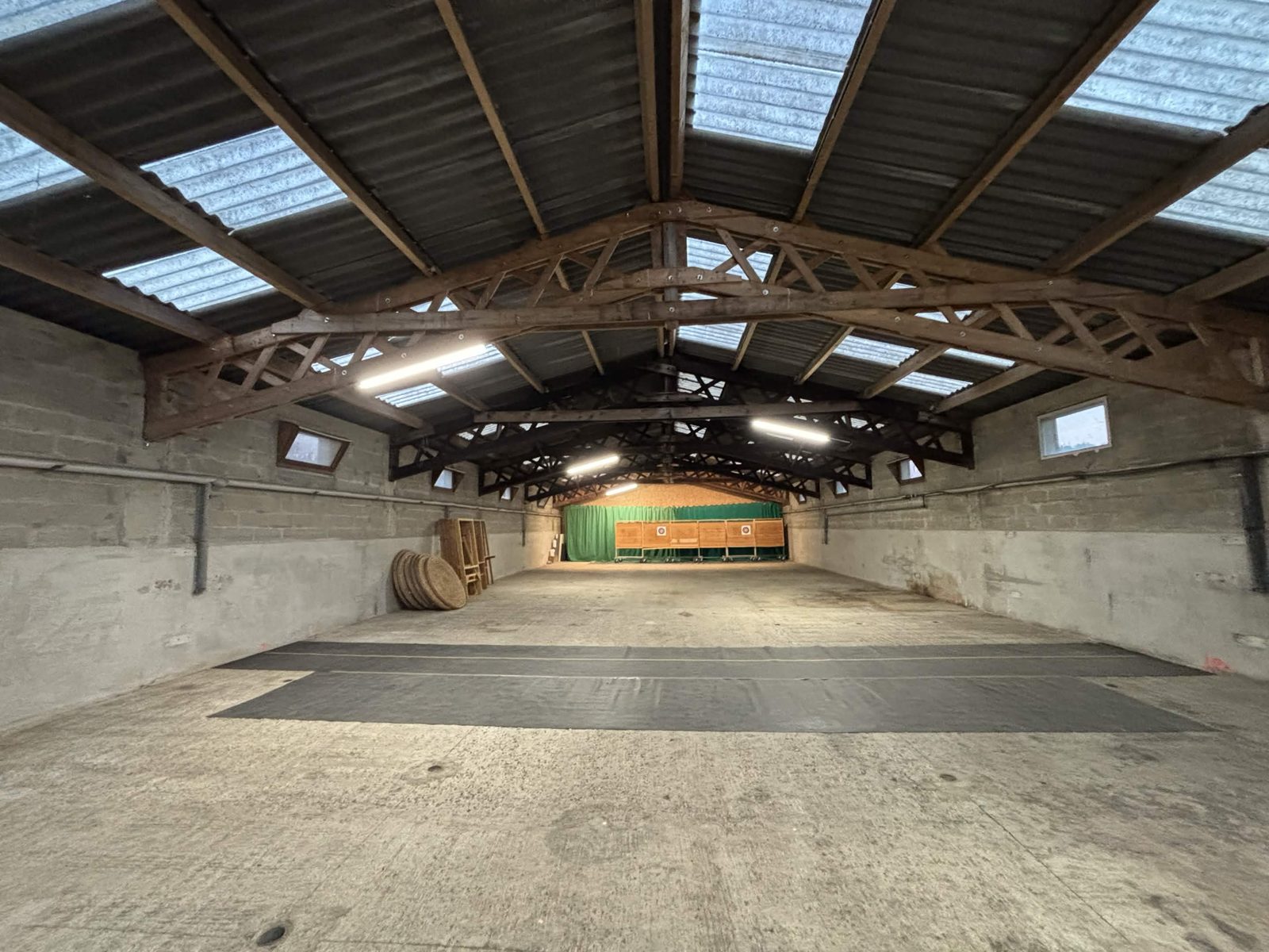 Salle intérieure du club : grande charpente en bois, cibles et butts au fond